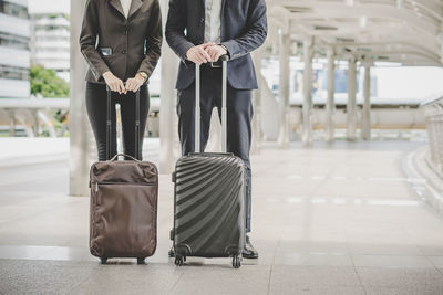 Low section of business people with luggage talking while walking on street