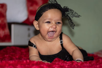 Cute baby girl with mouth open lying on bed