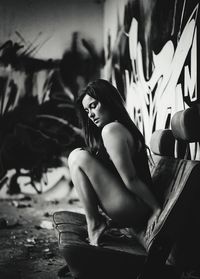 Sensuous woman crouching on chair at abandoned factory