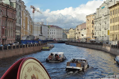 Boats moored in city against sky