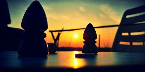 Close-up of silhouette on table against sky during sunset