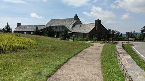 Footpath amidst houses on field against sky