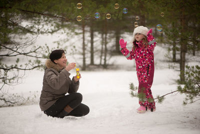 Mother and daughter with bubbles on snow