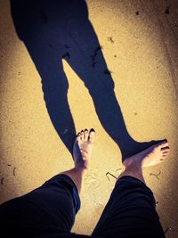 Low section of man standing on sand