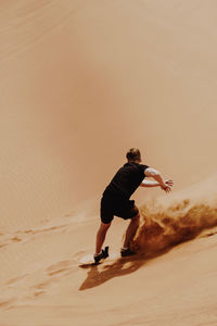 Man sandboarding in desert