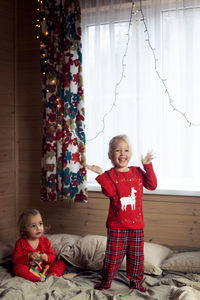 Full length of boy playing with teddy bear while standing against wall