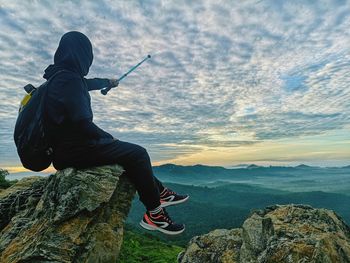 Rear view of man on rock against sky