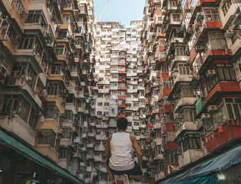 Rear view of man standing on street amidst buildings