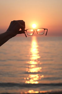 Person hand against orange sky during sunset