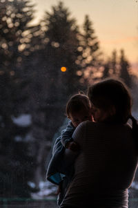 Woman with son standing at sunset