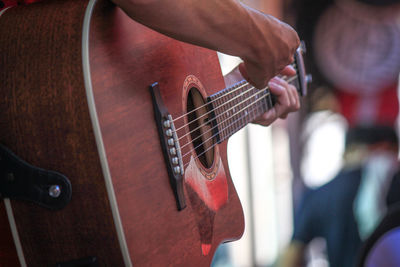 Midsection of man playing guitar