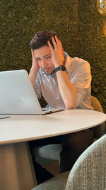 Midsection of man using mobile phone while sitting on table