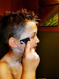 Close-up of boy shaving at home