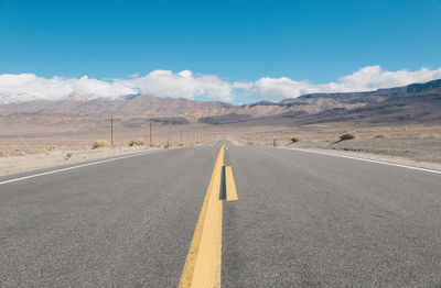 Road leading towards mountains against sky