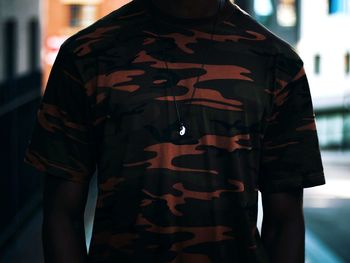 Midsection of man wearing yin yang symbol pendant