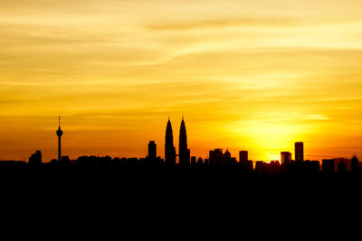 Silhouette cityscape against the sky at sunset