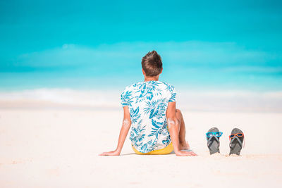 Rear view of people at beach against sky