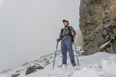 Rear view of man standing on snowcapped mountain