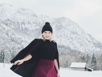 Portrait of mid adult woman standing on snow covered mountain against sky