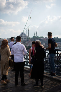 Rear view of people walking in city against sky