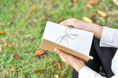 Midsection of person holding paper on field