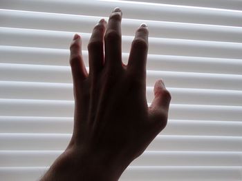 Cropped hand of woman touching window blinds
