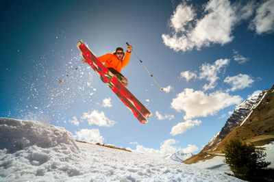 Fly young caucasian man jumping from a springboard on skis