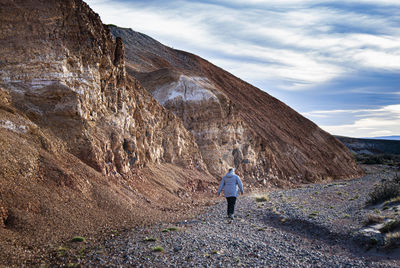 Rear view of woman walking by rock formation