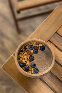 Wooden bowl of flaxseed or linen porridge decorated with blueberry, almond and granola 