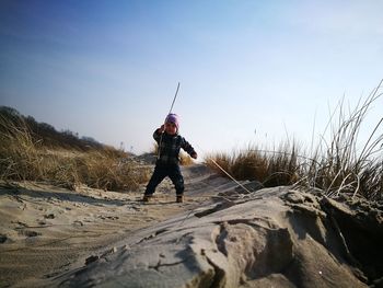 Child standing on sand against clear sky