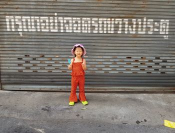 Full length of girl gesturing while making a face against closed shutter