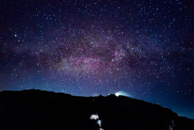 Low angle view of silhouette mountain against star field