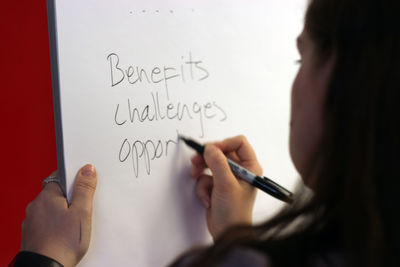 Woman writing on whiteboard against red background