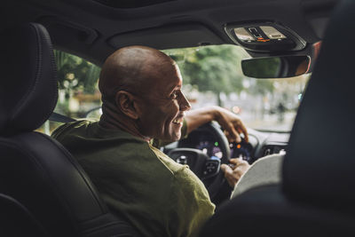 Smiling mature man looking away while sitting in car