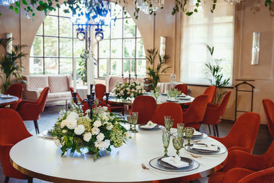 Restaurant hall with white tables and red exquisite chairs, decorated with floral arrangements 