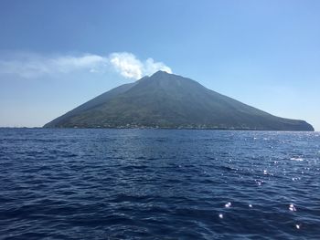 Scenic view of sea and mountains against blue sky