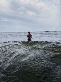Rear view of man in sea against sky