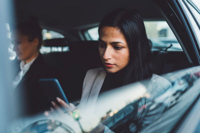 Portrait of young woman using mobile phone while sitting in car