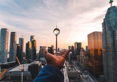 Cropped image of hand with crystal ball against modern buildings 