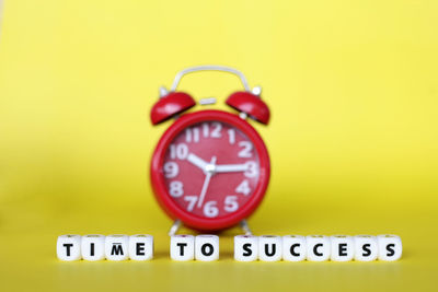 Close-up of clock on yellow background