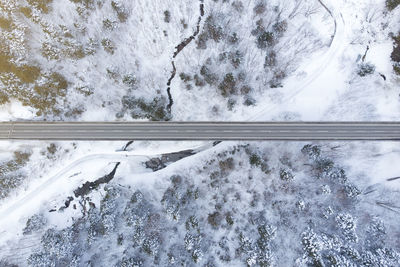 Directly above shot of road amidst snow covered forest during winter