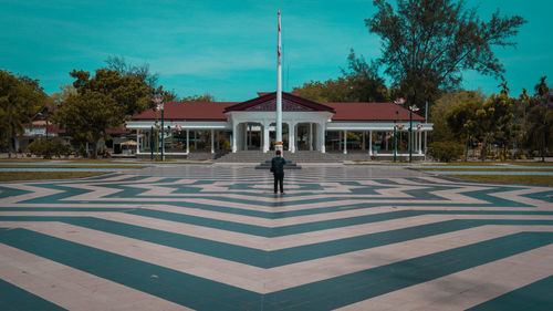 Man standing by building against sky