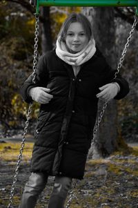 Portrait of a smiling young woman with swing in winter