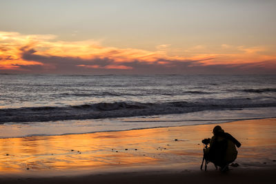 Man on beach against sky during sunset