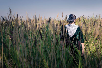 Woman wearing mask standing amidst farm