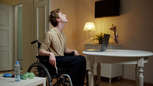 Side view of man sitting on table at home