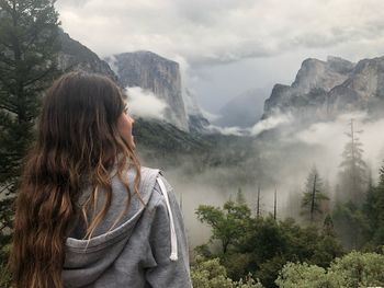 Rear view of woman looking at mountains during foggy weather