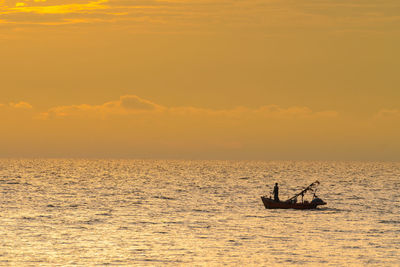 Silhouette people on boat on sea against sky during sunset