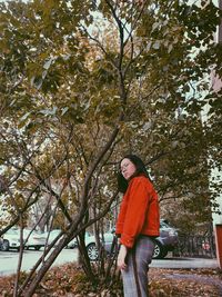 Portrait of woman standing by tree