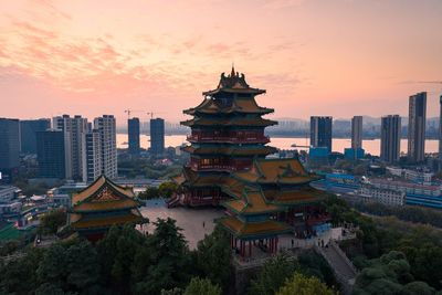 Temple by building against sky during sunset in city